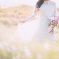 ピンク色のバラのブーケを持つ花嫁の野原での撮影の写真