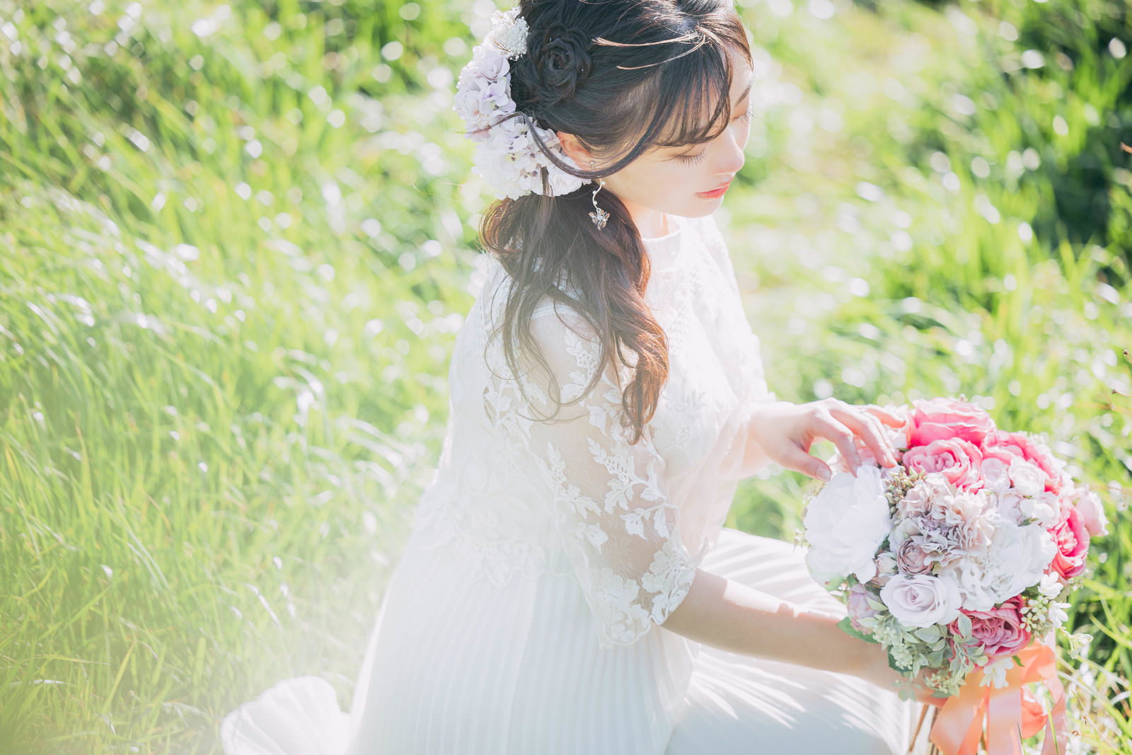ウェディングドレスを着た女性がピンク色と白のバラのブーケを手にして花を数えている［モデル：河村友歌］