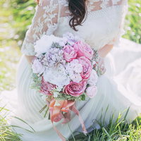 ピンクと白のバラを合わせたブーケを持った白いドレス姿の女性の写真