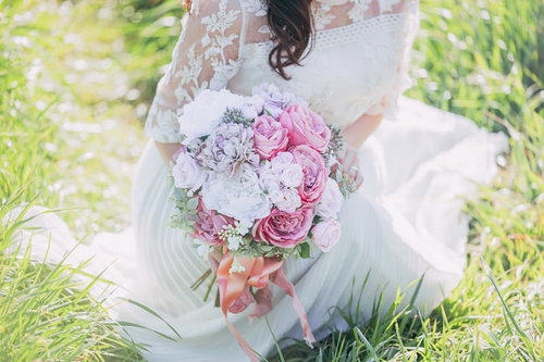 ピンクと白のバラを合わせたブーケを持った白いドレス姿の女性