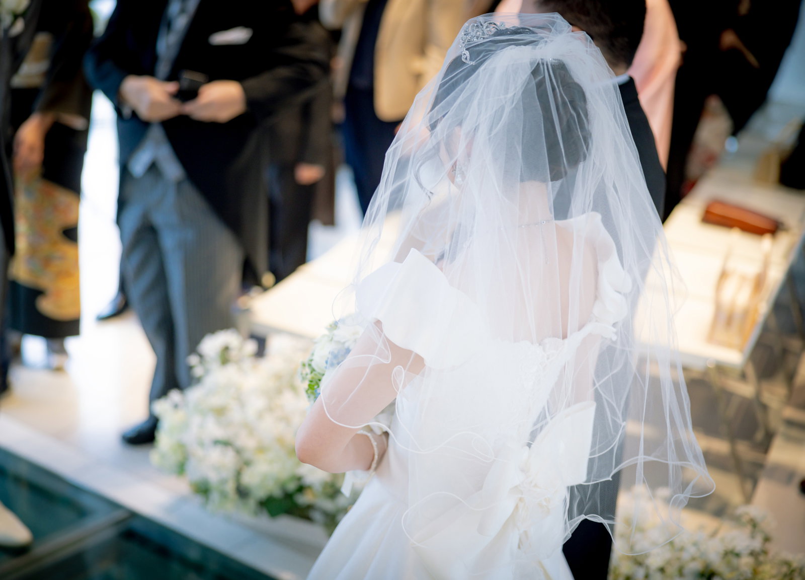 ベールをかぶったウエディングドレス姿の花嫁がバージンロードを歩む［モデル：河村友歌］