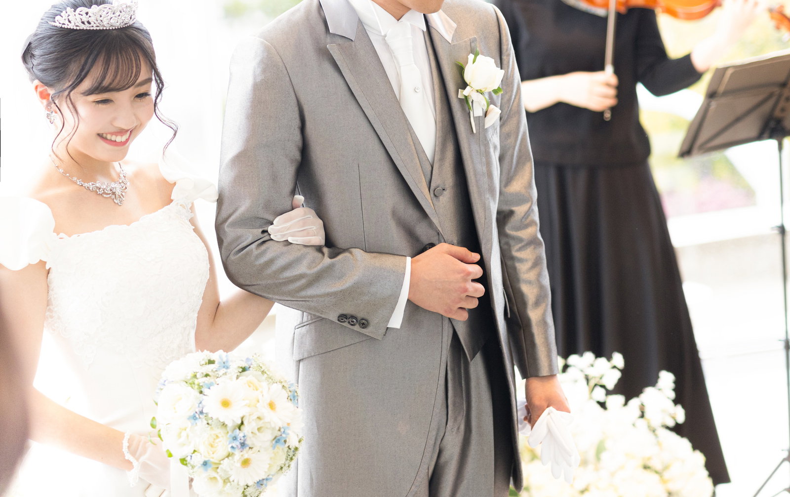 結婚式で白いブーケを持つウエディングドレス姿の新婦と新郎［モデル：河村友歌］