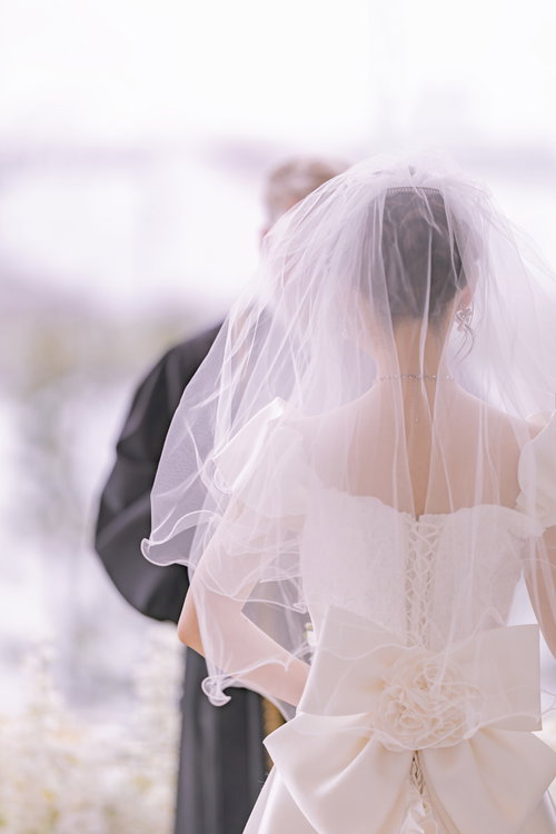 誓いの言葉を交わす花嫁の後ろ姿、白いベールとウエディングドレス