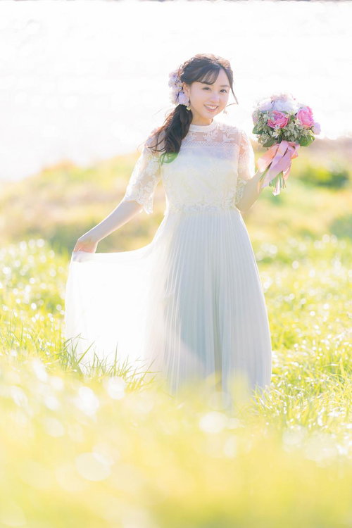 ブーケを持った花嫁の女性がウェディングドレスで笑顔で立つポートレート