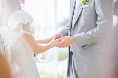 結婚式で指輪交換を終えて花嫁の手をそっと握る新郎の手元