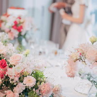 ピンクと赤のカーネーションに囲まれた結婚披露宴のメインテーブルの写真