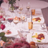 ピンクの花に彩られた披露宴の新郎新婦の席の写真