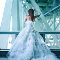 高架下で立つウェディングドレス姿の女性の後ろ姿の写真