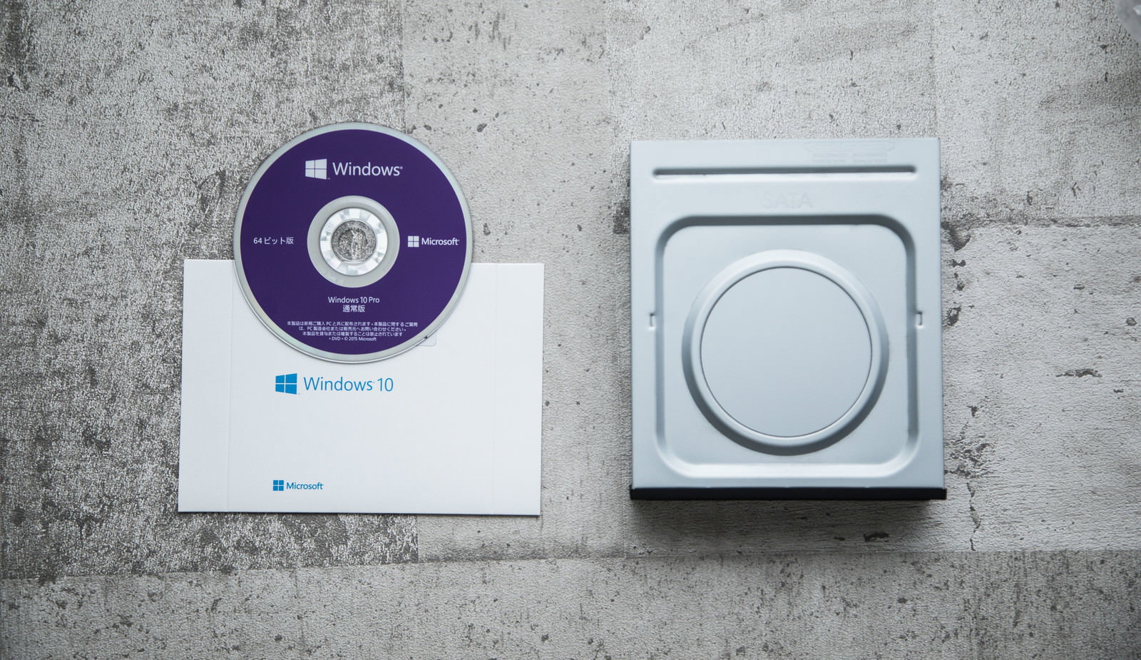 Embedded DVD drive and OS installation disc on a concrete background