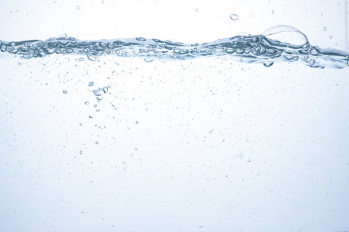 水槽のミネラルウォーターに浮かぶ気泡と水面の断面