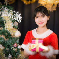 クリスマスツリーの前でプレゼントを持つサンタコス姿の女性の写真