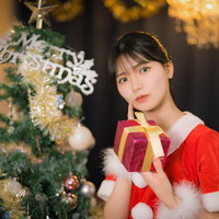 クリスマスツリーとサンタコスの女性がプレゼントを持つの写真