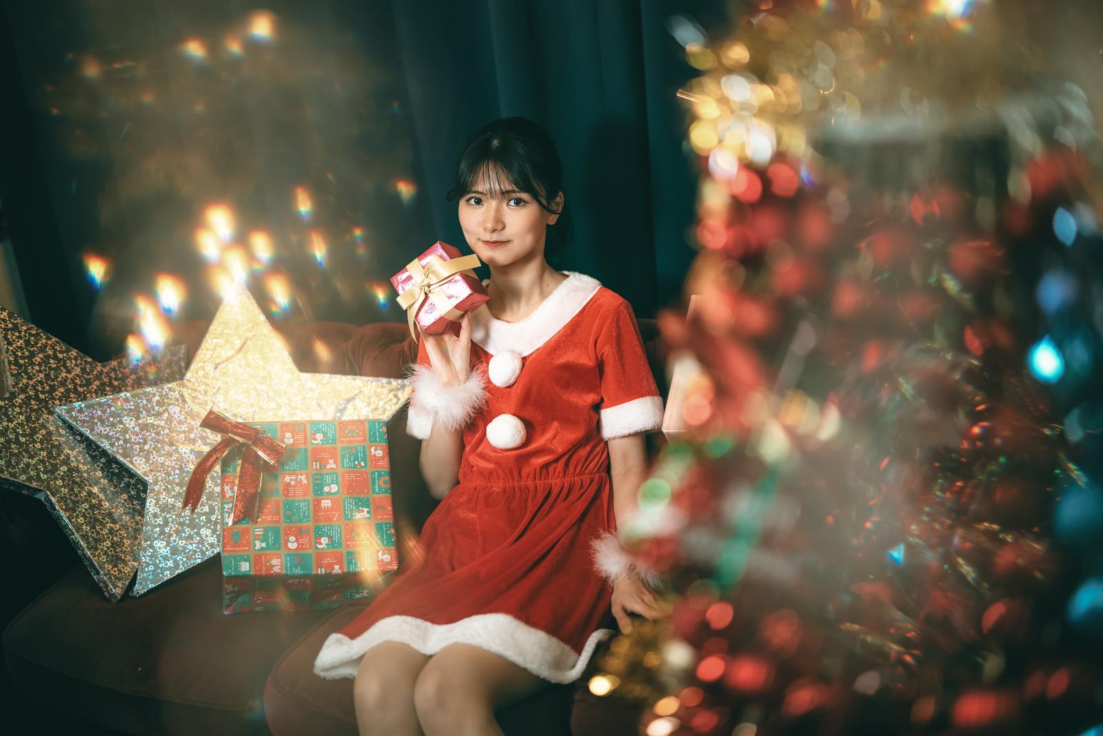サンタコスプレを着た女性がプレゼント箱を持つクリスマスルームの写真［モデル：モデルリリース］