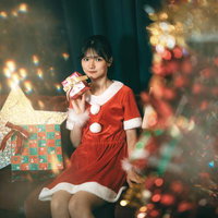 クリスマスルームでサンタコスプレのプレゼントを持つ女性の写真