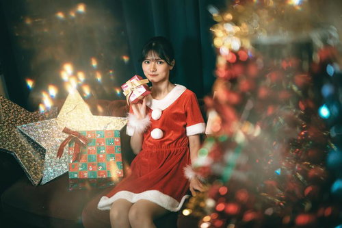 クリスマスルームでサンタコスプレのプレゼントを持つ女性