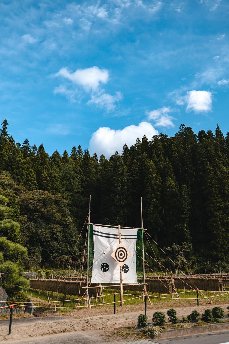 古殿八幡神社の流鏑馬の的と稲架掛けが青空の下に立つ景観