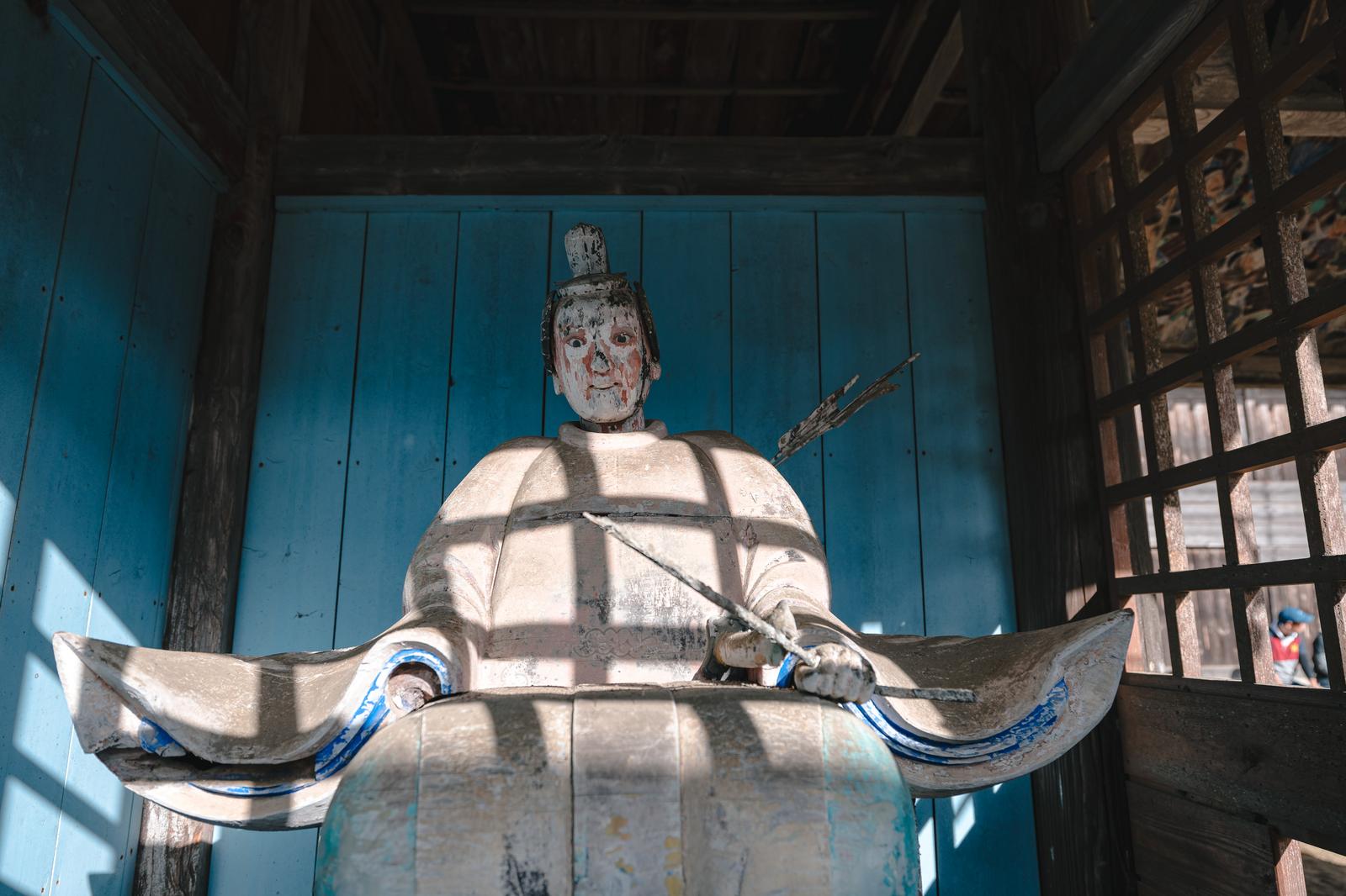 古殿八幡神社の境内で窓格子の影が落ちる白い像