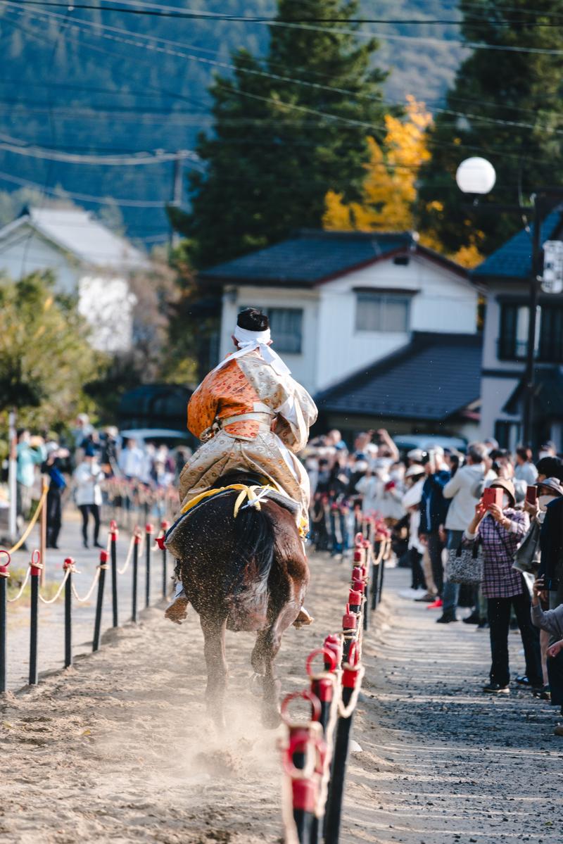 古殿八幡神社の流鏑馬で土煙を上げて疾走する馬と白衣の射手