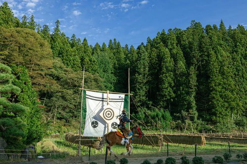 古殿町の稲架掛け背景に流鏑馬で的に命中させた瞬間