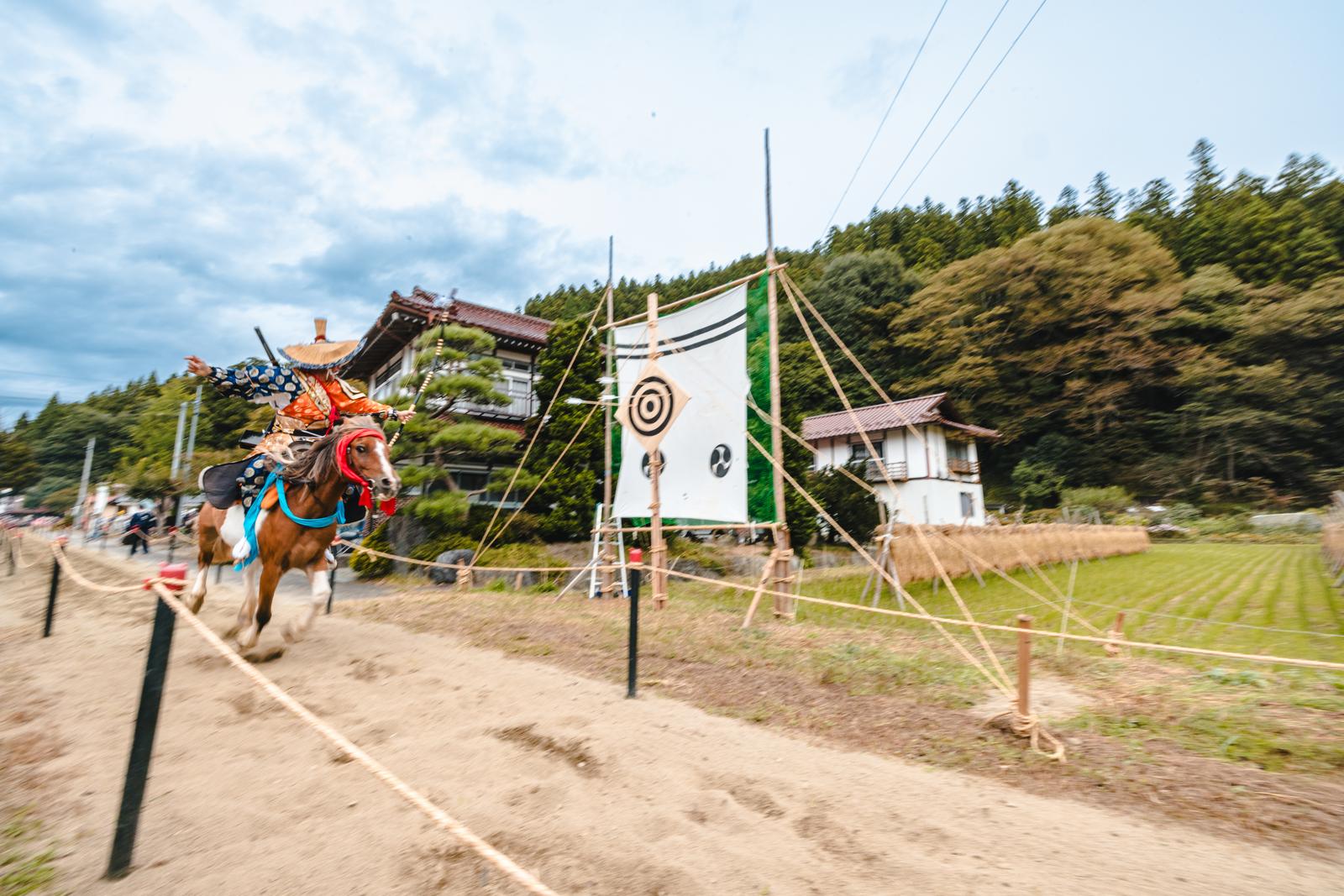 古殿八幡神社で流鏑馬を実施する赤い装束の射手が馬で砂地を疾走している