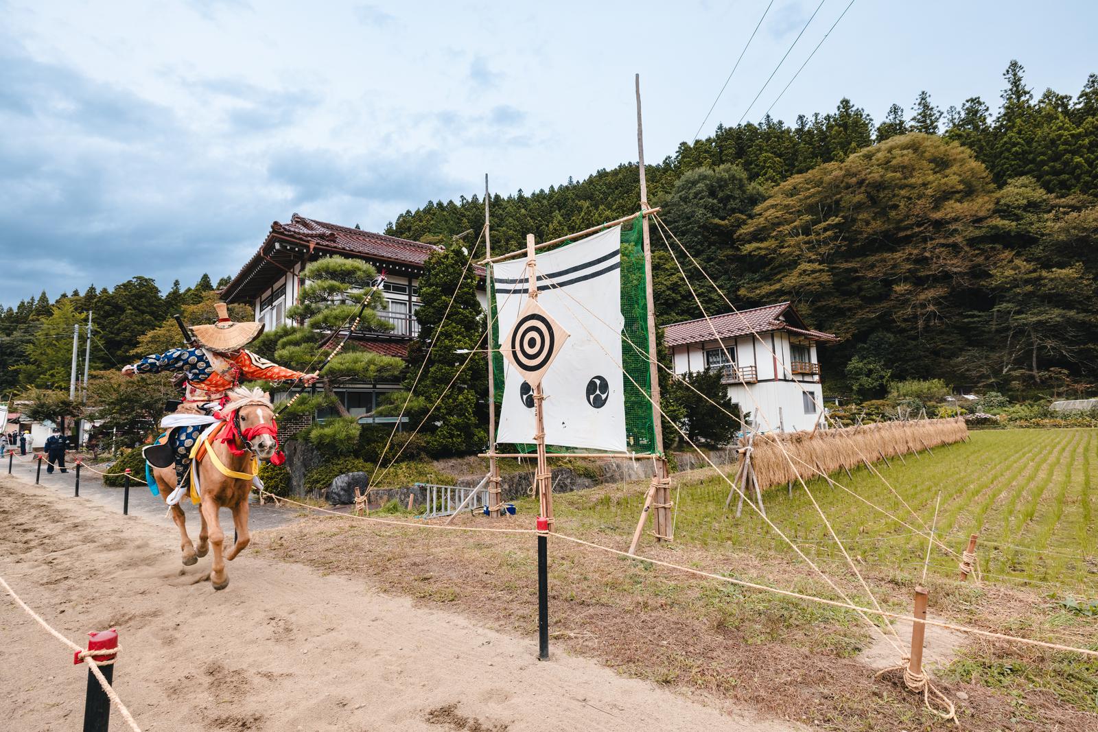 古殿八幡神社の流鏑馬で、全速力で駆ける馬の上から放たれた矢が的に向かう光景