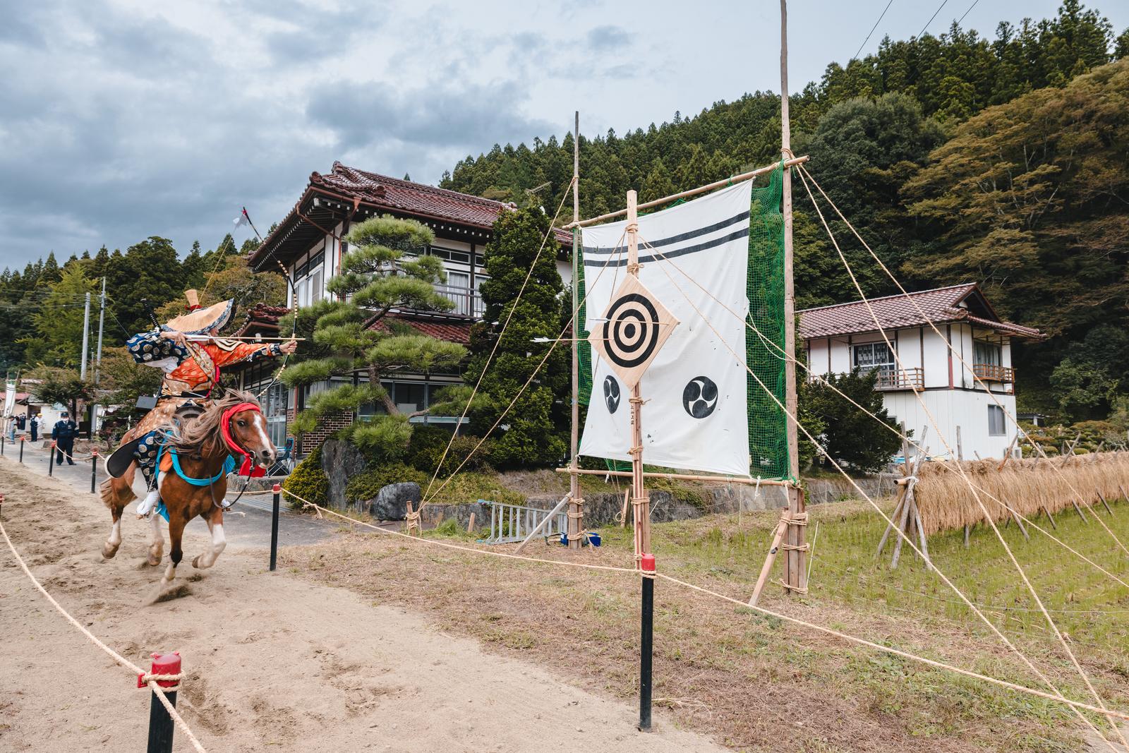 古殿八幡神社の流鏑馬で、馬上の射手が白い的に矢を放つ瞬間