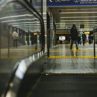 終電時間帯のエスカレーターと改札での乗客の流れの写真