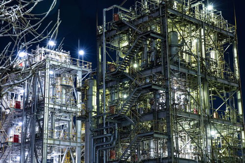 夜の工場細部に浮かぶ配管と光芒が織りなす産業景観