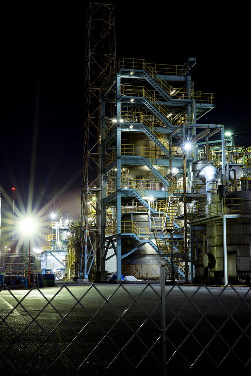 大中小の光芒と工場夜景の光景、鉄骨と金網フェンスに映る夜間照明