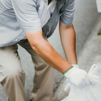 ポイ捨てされたゴミを拾うハンチング帽姿の男性の写真