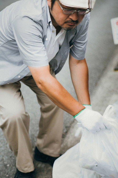 ポイ捨てされたゴミを拾うハンチング帽姿の男性
