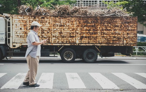 横断歩道を渡りながらスマートフォンを見る男性
