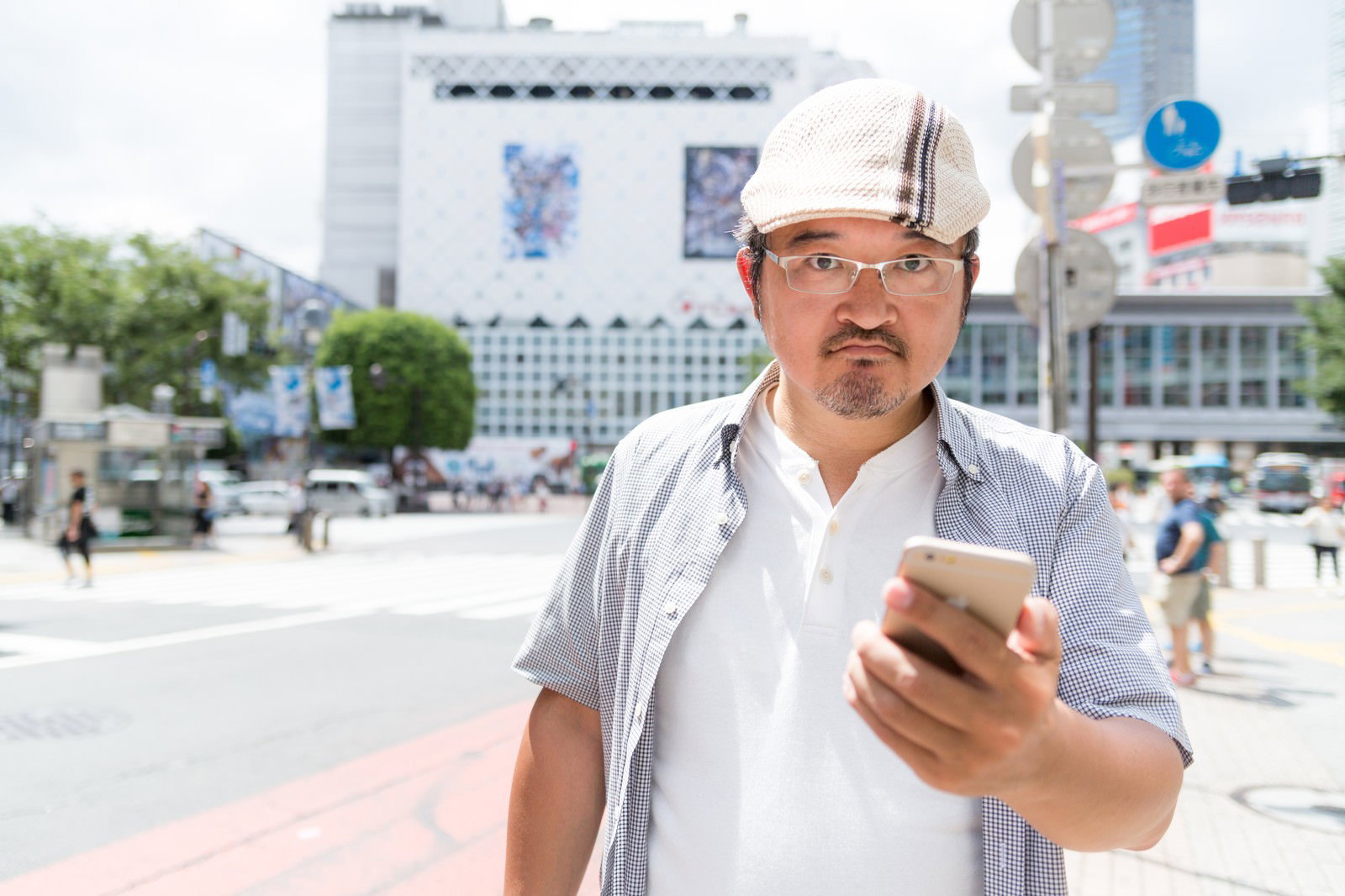 渋谷でスマートフォンを見るハンチング帽の男性［モデル：ナリシゲ］