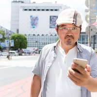 渋谷でスマートフォンを持つハンチング帽姿の男性の写真