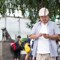 渋谷のハチ公像前でポケモンゲットに熱中するハンチング帽の男性の写真