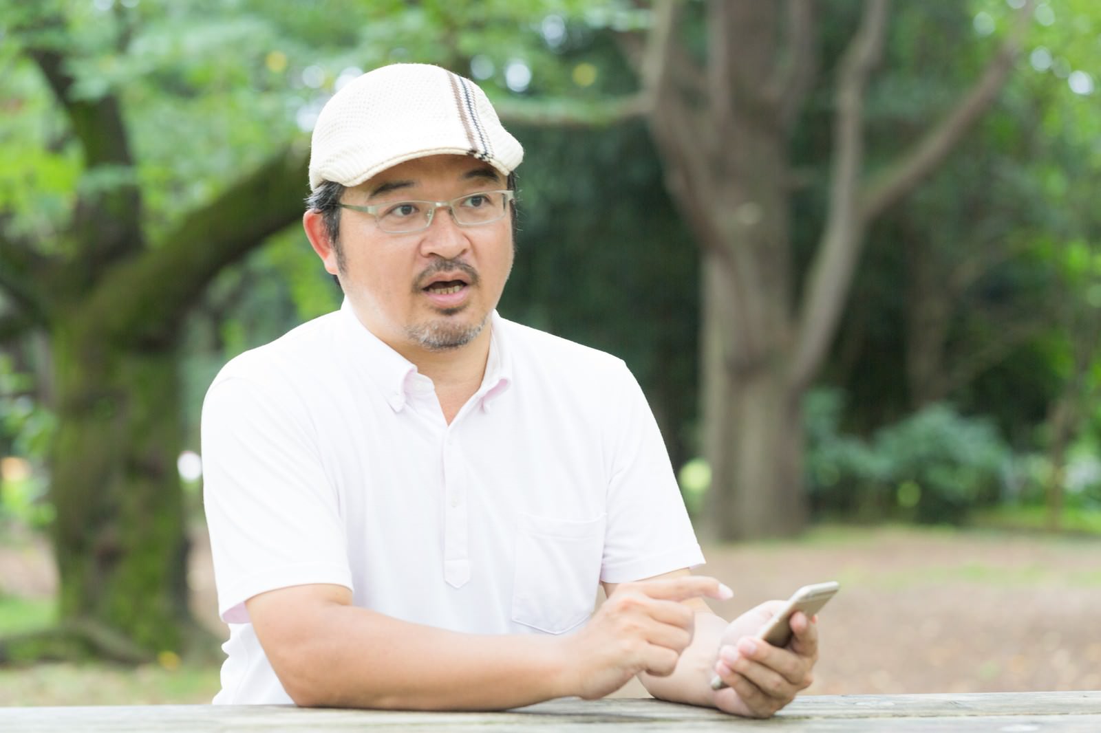 スマートフォンを持ち話す眼鏡の男性［モデル：ナリシゲ］