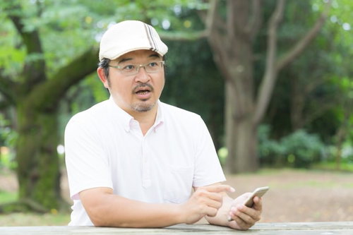 大人気のスマートフォン用ゲームに否定的な意見を述べるハンチング帽姿の男性