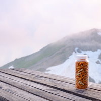 登山のお供にナルゲンボトルに入った柿ピー、背景に後立山連峰の写真