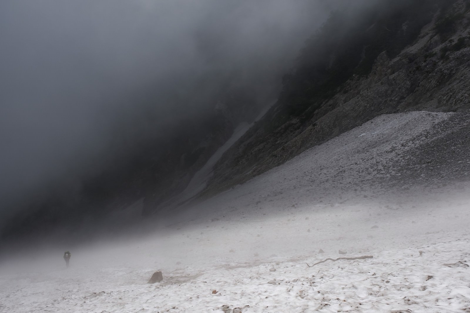 ガスと霧に包まれた白馬大雪渓を歩く登山者の姿
