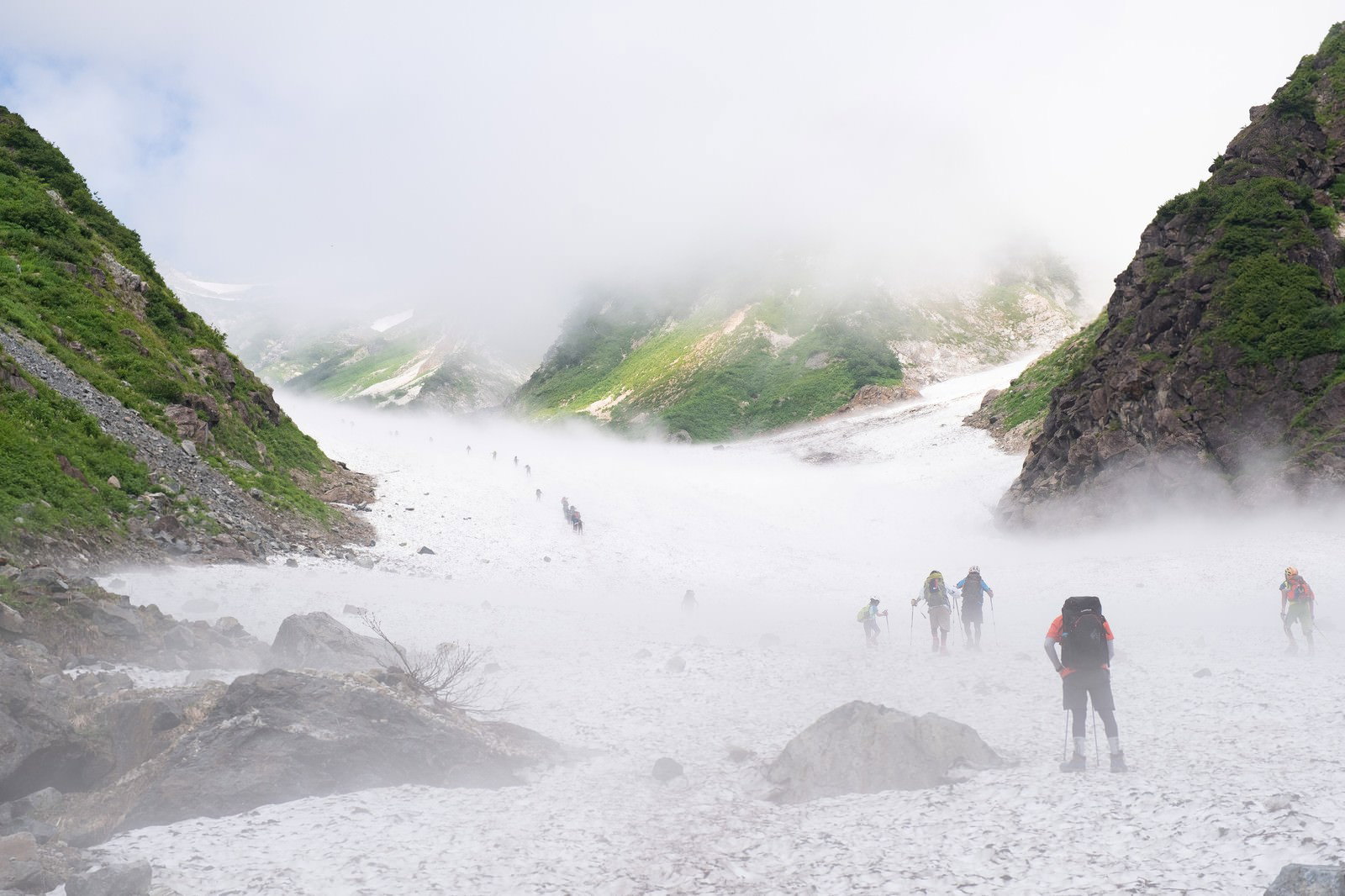 白馬大雪渓の霧に包まれた斜面を登る複数の登山者達