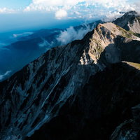 夕日が当たらない杓子岳の切り立つ山肌と稜線の写真
