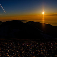 夕日に照らされた白馬岳の登山道を歩む登山者たちの写真