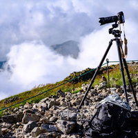 白馬岳の山頂で三脚と一眼レフを使って山岳写真を撮影中の写真