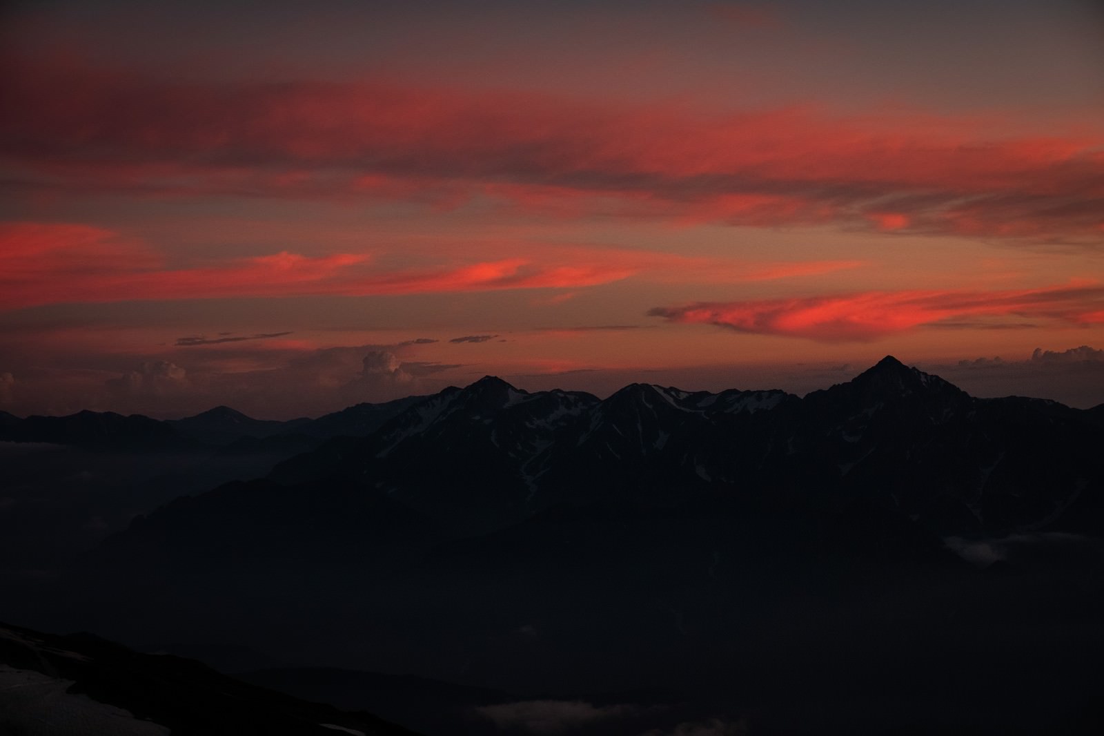 夕焼け空をバックに暗いシルエットで浮かび上がる立山連峰の山並み