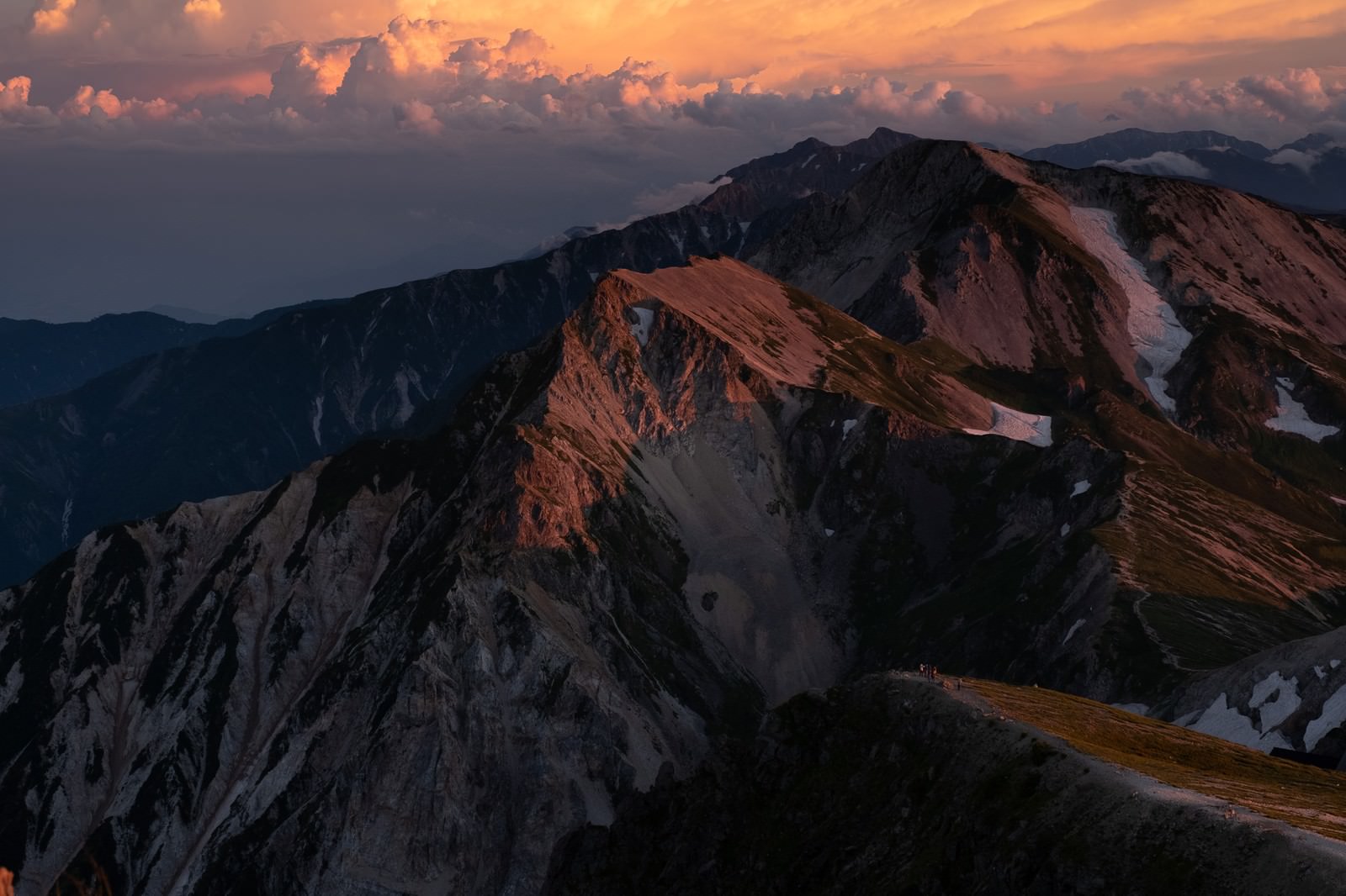 夕焼けに染まるオレンジ色の白馬連峰の山々と険しい山稜線