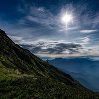 朝の光芒と白馬岳稜線の緑の写真