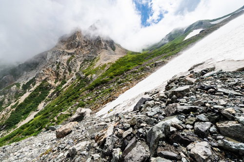 白馬岳の白馬大雪渓と荒々しい岩肌を望む登山風景