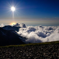 白馬岳から見る陽の光と山並みのシルエットの写真