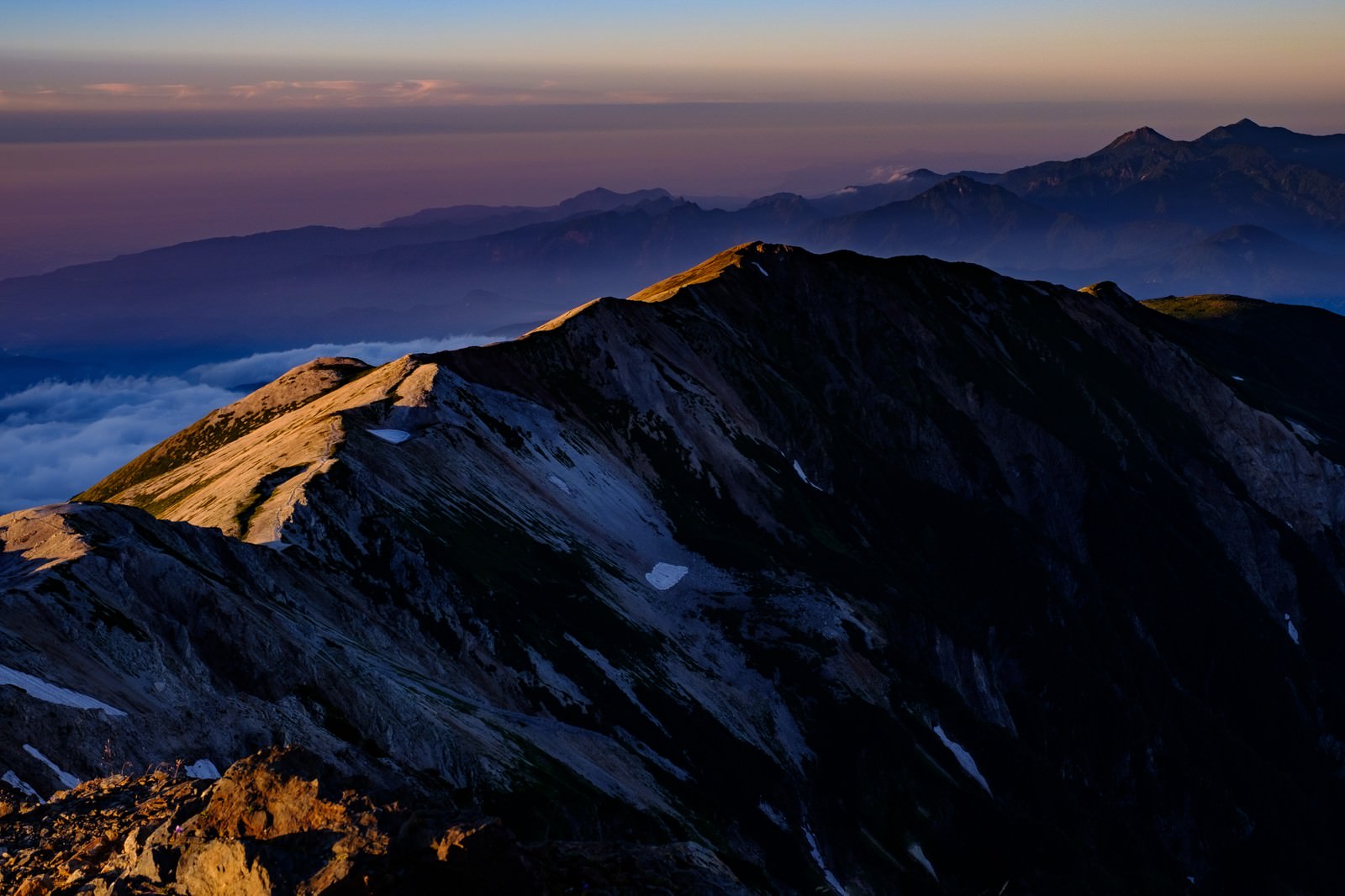 白馬岳山頂から見た夕日に染まるオレンジ色の山々の稜線
