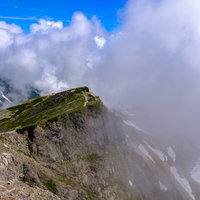 白馬岳の山頂から望む稜線に連なる北アルプスの山々の写真